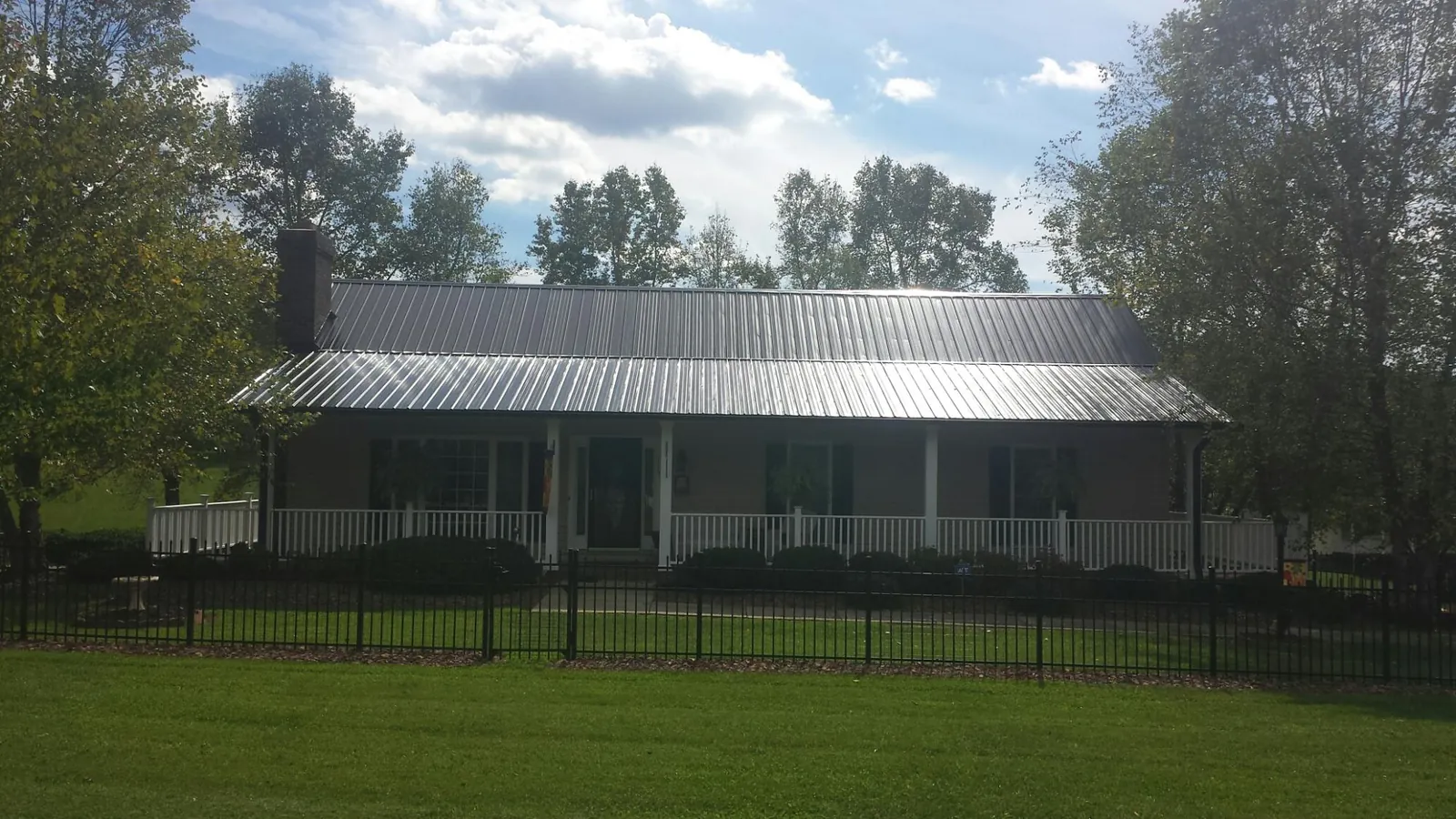 Gray metal roof on a brick ranch with a full width front porch — Gutter Guard Installation work by our crew in Hope